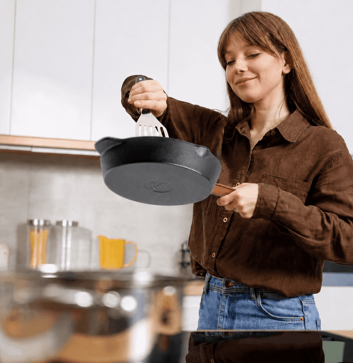 Frau hält eine Tecor Gusseisenpfanne mit Pfannenwender in der Küche